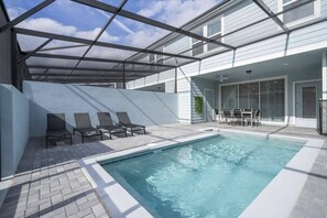 A swimming pool with a covered patio area, lounge chairs, and a table with chairs. - Marvelous 5 bedroom home for vacation in Orlando with private pool (Davenport)
