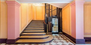 A grand staircase with a handrail, leading to a door with a metal gate. - Elegant 220m² Abode In Grands Boulevards: Expansive Living & Refined Interiors (Paris)