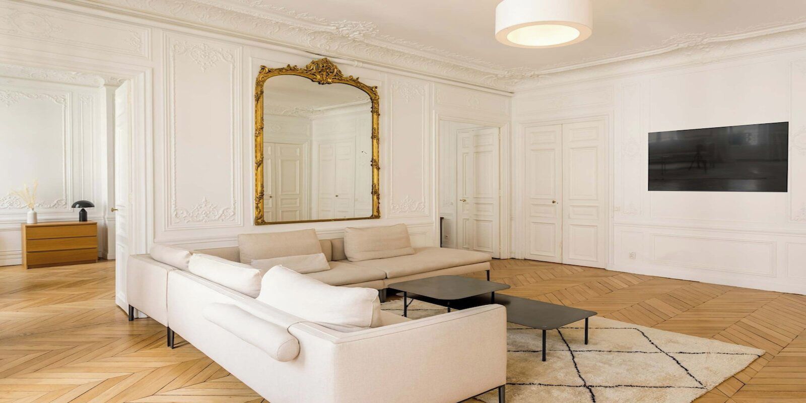 A modern living room with a sofa, a coffee table, a large mirror, and a painting on the wall.
