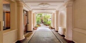 A corridor with columns, potted plants, and a view of greenery outside. - Elegant 220m² Abode In Grands Boulevards: Expansive Living & Refined Interiors (Paris)