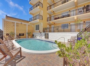 A hotel pool area with a clear pool, lounge chairs, and a building with balconies. - Beautiful Oceanview with Private Balcony on Hollywood Boardwalk (Hollywood)