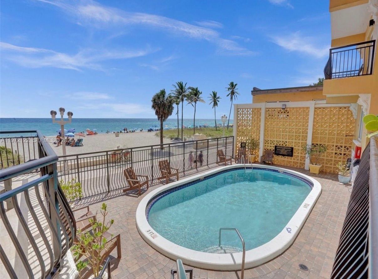 Una piscina con vista a la playa y palmeras.