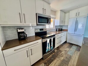 Een moderne keuken met witte kasten, roestvrijstalen apparatuur en een behangpaneel.