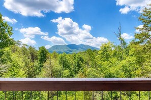 Blick auf eine gebirgige Landschaft mit einer Holzterrasse im Vordergrund.