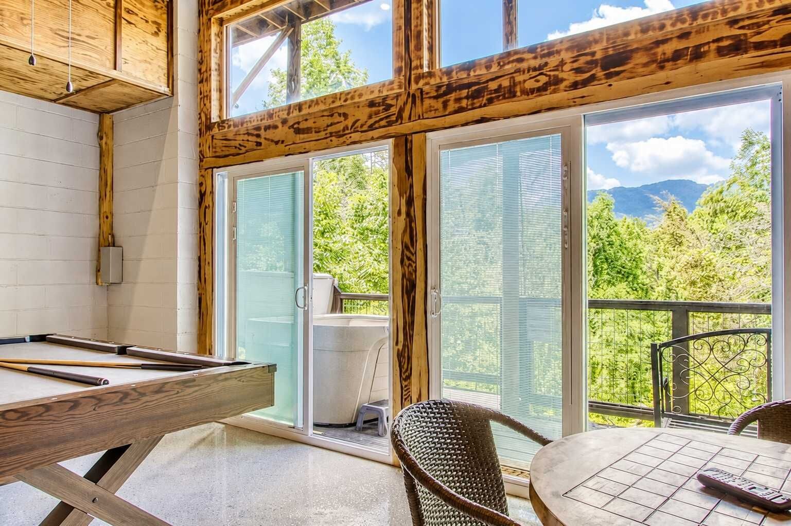 Une pièce avec une table de billard, un fauteuil en osier et une vue sur un balcon doté d’une balustrade.