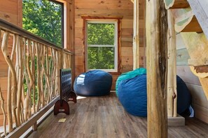 A wooden deck with a railing, a window, and two bean bags. - 4-Bedroom Cabin with Indoor Pool Waterfall & Game Room Near Pigeon Forge (Sevierville)