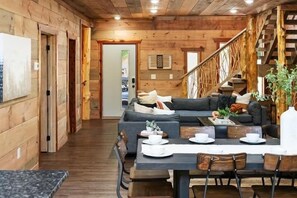A cozy wooden interior with a dining area, sofa, and staircase. - 4-Bedroom Cabin with Indoor Pool Waterfall & Game Room Near Pigeon Forge (Sevierville)