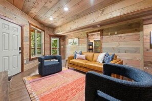 A log cabin interior with a sofa, armchair, and a rug. - 4-Bedroom Cabin with Indoor Pool Waterfall & Game Room Near Pigeon Forge (Sevierville)