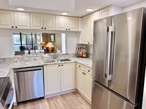 A modern kitchen with stainless steel appliances, marble countertops, and light-colored cabinetry. - 4108 - Beautifully Updated 2-bed/2-bath condo close to Beaches and IMG Academies (Bradenton)