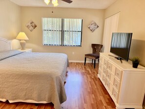 A bedroom with a bed, a chair, a television, and a dresser.