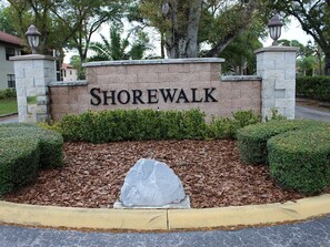 A sign with the name 'Shorewalk' in a landscaped area with trimmed hedges and mulch. - 4108 - Beautifully Updated 2-bed/2-bath condo close to Beaches and IMG Academies (Bradenton)