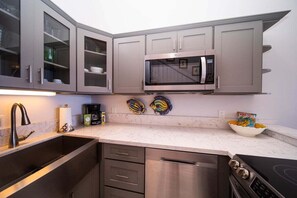 A modern kitchen with grey cabinets, a stainless steel microwave, a dishwasher, and a stove.