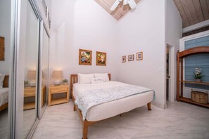 A bedroom with a bed, bedside tables, a mirror, and artwork on the wall.