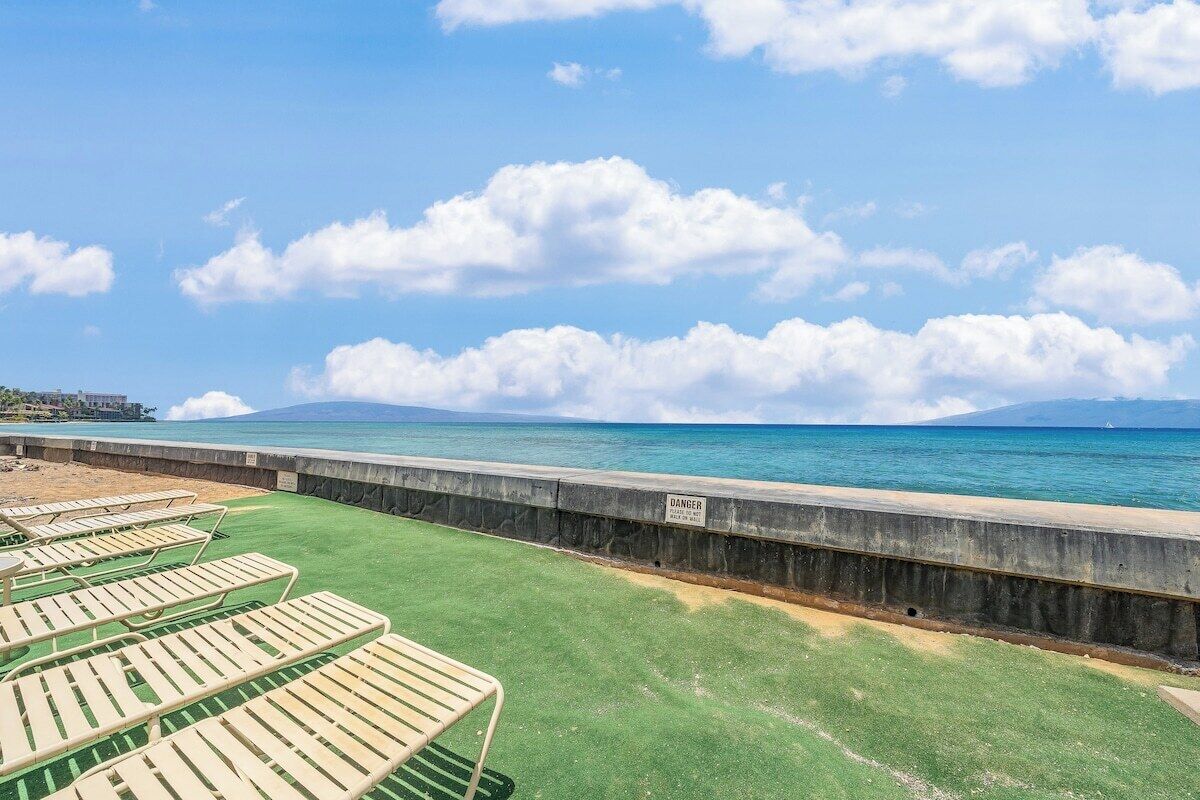 A beachside lounge area with sun loungers and a concrete barrier.