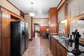 A kitchen with wooden cabinets, a stainless steel refrigerator, a sink, and a dining area in the background. - Spacious 5BR Home in Meridian (Meridian)