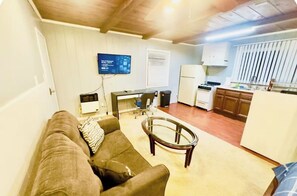A living room with a couch, a coffee table, and a TV mounted on the wall.