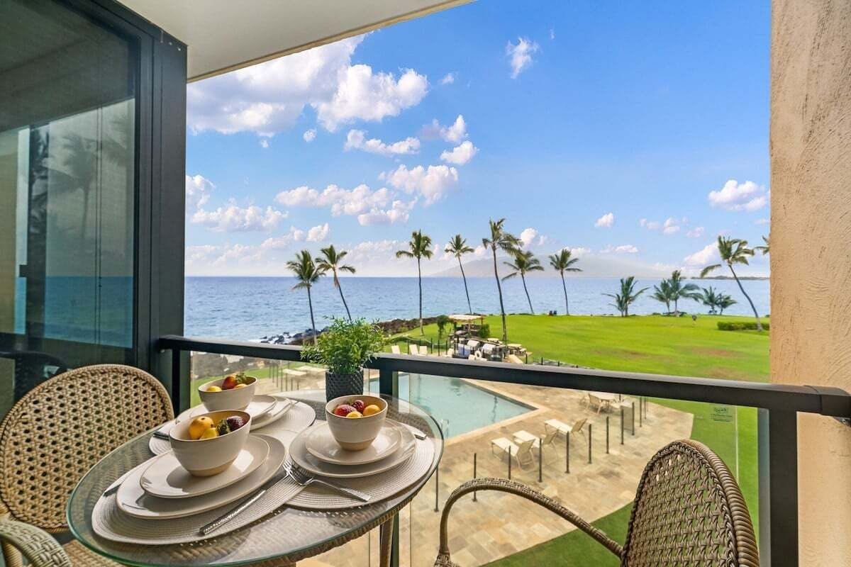 Un balcón con una mesa dispuesta para el desayuno, con vistas a una piscina y un campo de golf.