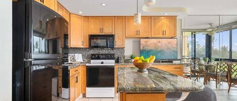 A modern kitchen with wooden cabinets, a black refrigerator, a stove, and a dining area with a table and chairs.