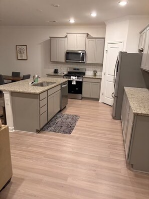 A modern kitchen with white cabinetry, a stainless steel microwave, and a built-in oven. - Beautiful Modern Home Near I-65 - Near Nashville (White House)