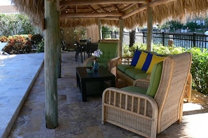 A covered outdoor seating area with wicker furniture, a table, and a view of a body of water. - Villa Bliss (Fort Lauderdale)