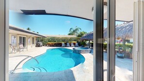 A swimming pool with lounge chairs and a thatched-roof structure. - Villa Bliss (Fort Lauderdale)
