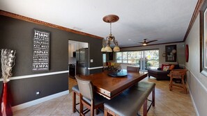 A dining area with a wooden table and chairs, a chandelier, and a view of the kitchen. - Villa Bliss (Fort Lauderdale)