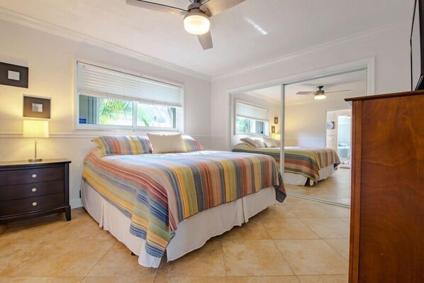 A bedroom with a bed, a dresser, a mirror, and a ceiling fan. - Villa Bliss (Fort Lauderdale)