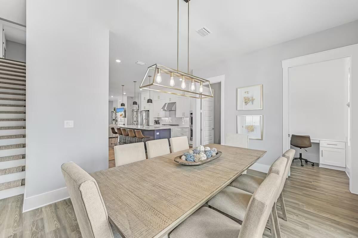 A modern kitchen with a dining area, featuring a wooden dining table, chairs, and a pendant light.