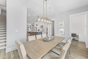 A modern kitchen with a dining area, featuring a wooden dining table, chairs, and a pendant light. - The Lookout (Panama City Beach)