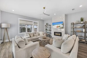 A modern living room with a sofa set, a coffee table, a fireplace, and a television. - The Lookout (Panama City Beach)