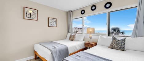 Habitación de hotel con dos camas, un ventilador de techo, una ventana con vistas y obras de arte en la pared.