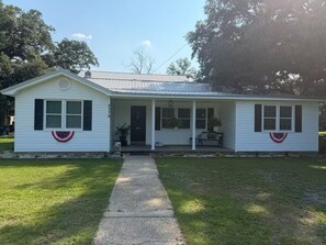 A single-story house with a front porch, a mailbox, and a front door.