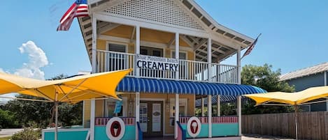 A creamery with a porch, American flags, and yellow umbrellas.