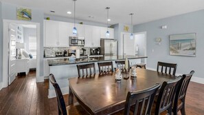 Una cocina moderna con gabinetes blancos, electrodomésticos de acero inoxidable y una isla central con asientos.