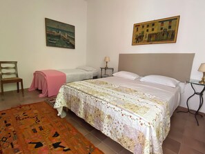 Ein Schlafzimmer mit einem großen Bett, einem Sessel, einem kleinen Tisch und zwei Bildern an der Wand.