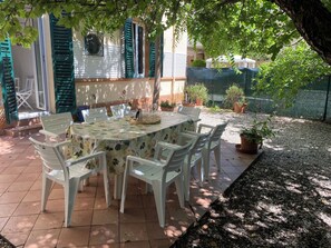 An outdoor dining area with a table and chairs, surrounded by potted plants and a gravel path. - Porzione di villa con giardino privato e A/C (Senigallia)