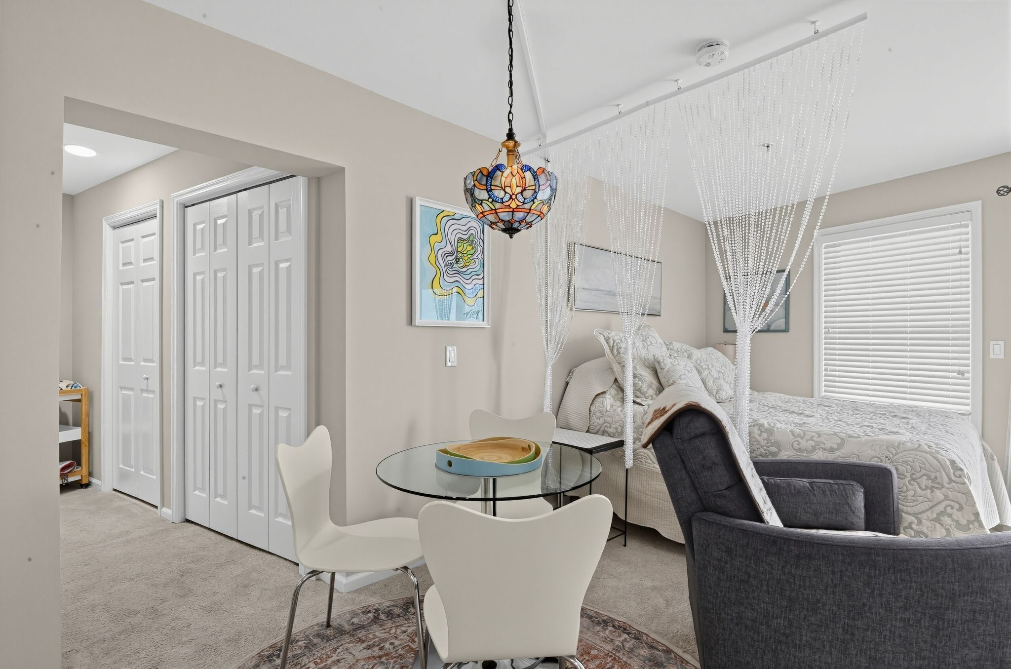 A modern bedroom with a canopy bed, a glass table, and a white chair.