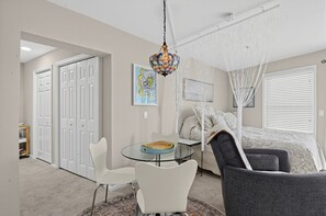 A modern bedroom with a canopy bed, a glass table, and a white chair.