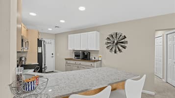 A modern kitchen with white cabinets, a granite countertop, and a central island with seating.