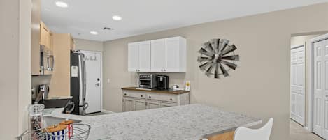 A modern kitchen with white cabinets, a granite countertop, and a central island with seating.