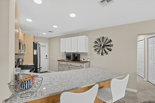 A modern kitchen with white cabinets, a granite countertop, and a central island with seating.