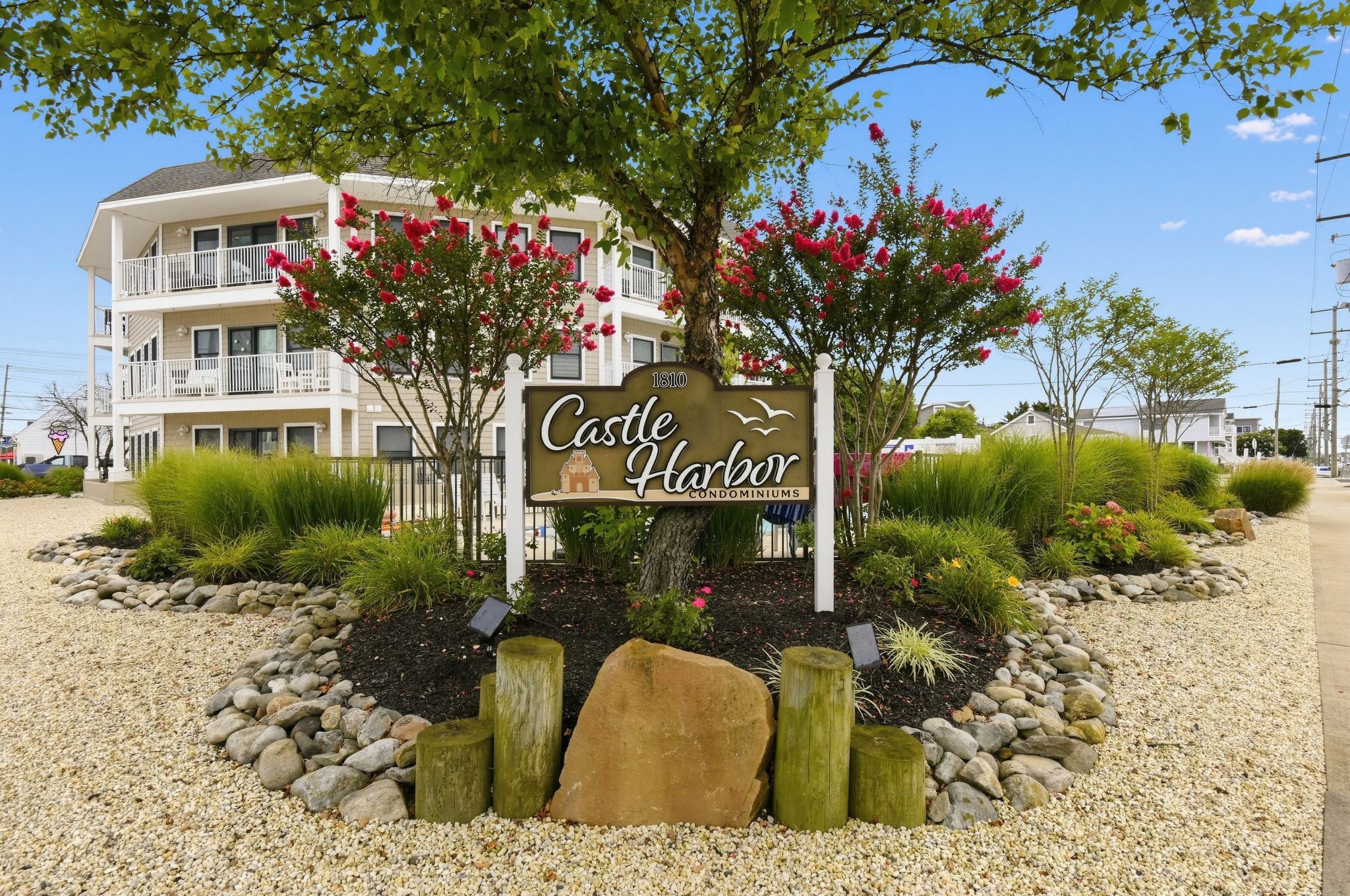 A sign for Castle Harbor Condominiums with a view of a multi-story building in the background.