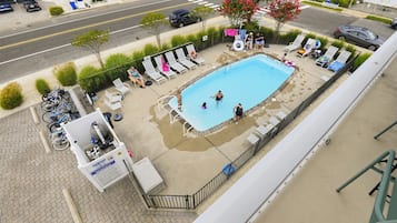 A rooftop pool area with lounge chairs, a pool, and a sign indicating a no diving zone.