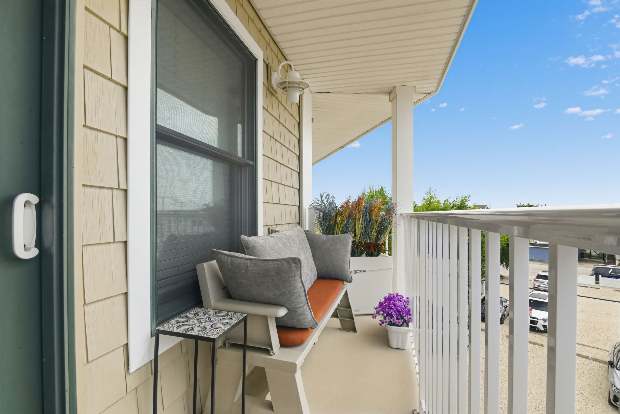 A balcony with a cushioned bench, a small table, and a potted plant.