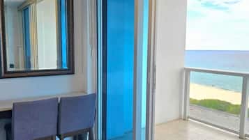 A balcony with a view of the sea, a sliding glass door, and a seating area with two chairs.