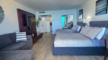 A modern bedroom with a large bed, a sofa, and a wooden floor.