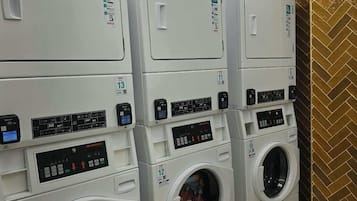 A row of stacked front-loading washing machines in a commercial setting.
