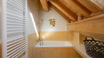 A bathroom with a bathtub, shower, and a towel rack.