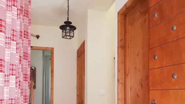 A hallway with a wooden door, a metal handle, and a key hanging on the door.