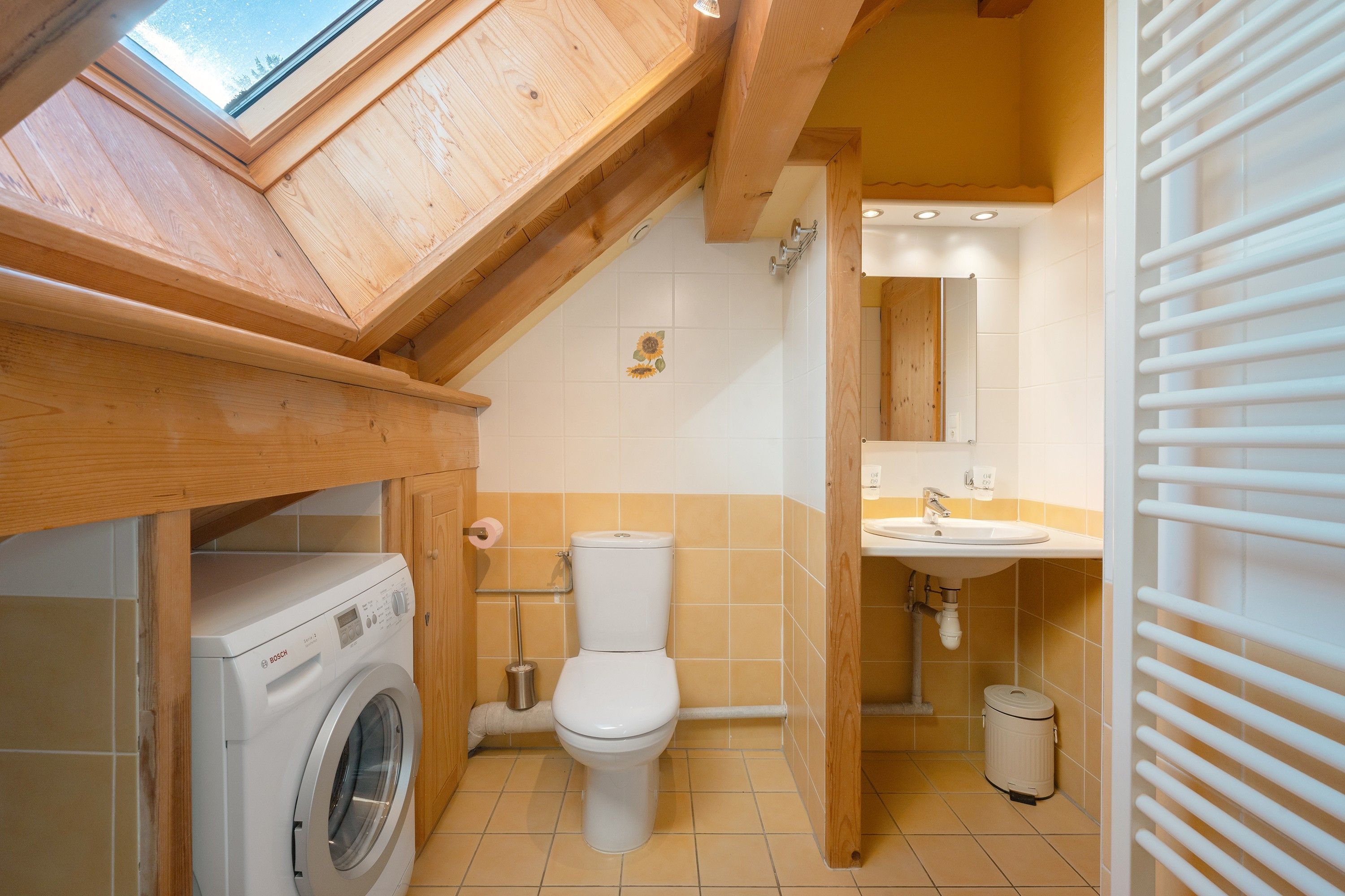 Une petite salle de bain équipée d’un lave-linge, de toilettes et d’un lavabo.